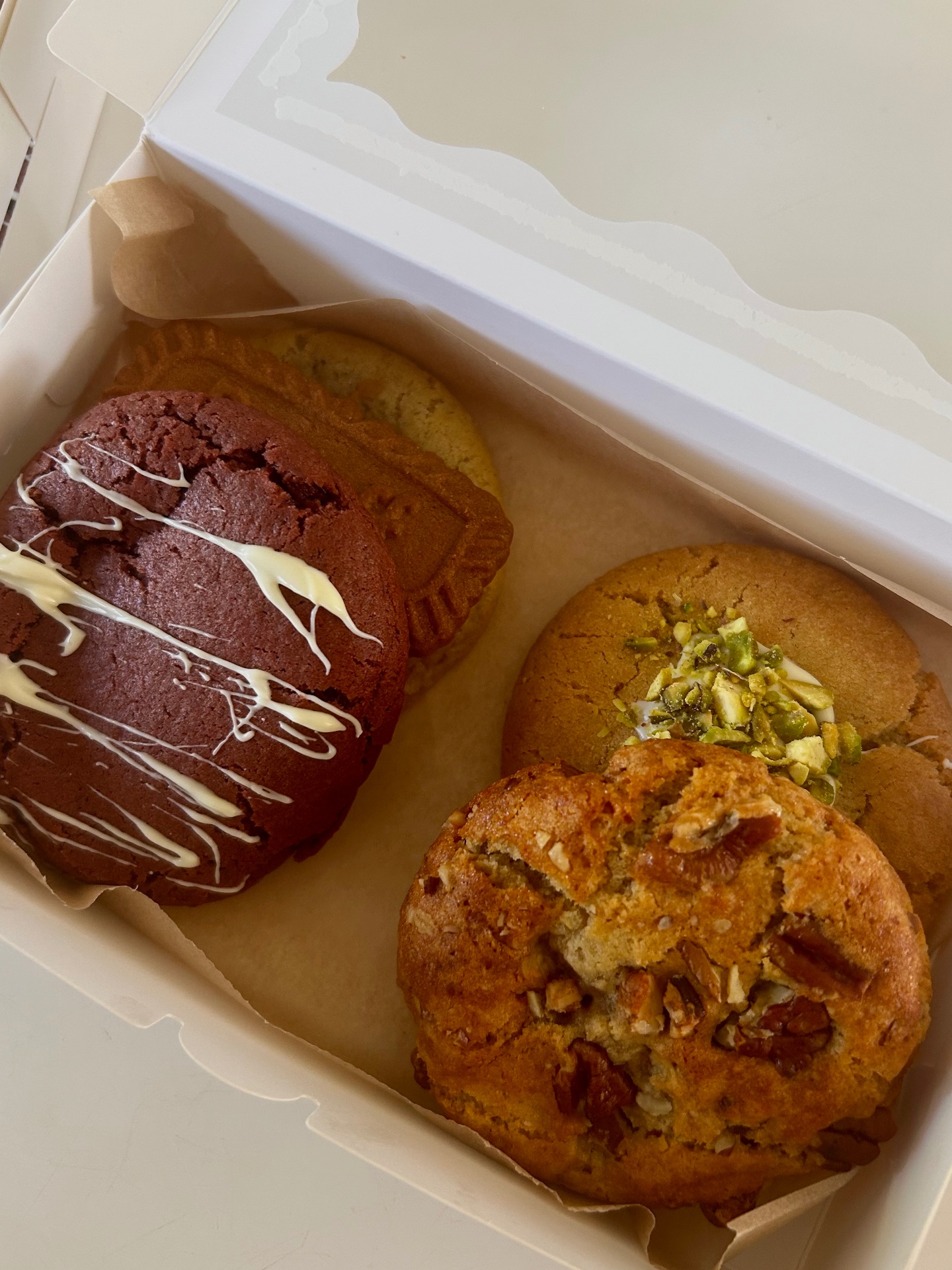 Box of 4 New York style cookies in a white bakery box on a home kitchen table with tea and linen